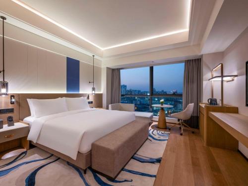 a bedroom with a large bed and a large window at Novotel Shanghai JingAn in Shanghai