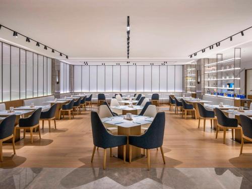 a restaurant with tables and chairs and windows at Novotel Shanghai JingAn in Shanghai