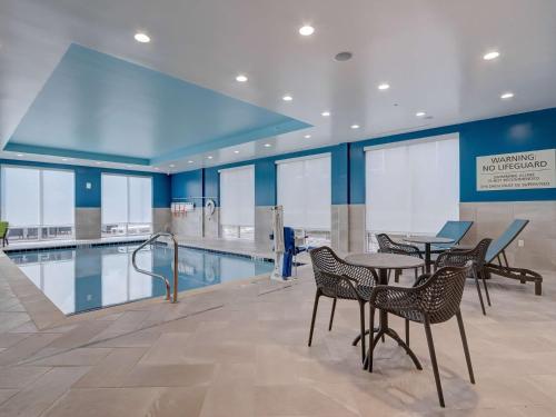 a swimming pool with tables and chairs in a building at Hampton Inn & Suites Cincinnati Midtown Rookwood in Cincinnati