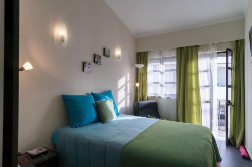 a bedroom with a bed with blue pillows and a window at NEW!! 1 Bedroom Center Tavira - R. Freiras in Tavira