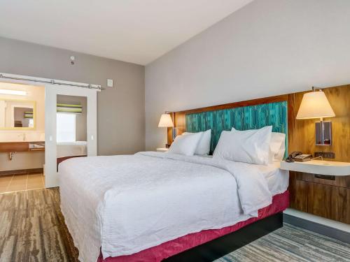 a hotel room with a large bed and a bathroom at Hampton Inn & Suites Cincinnati Midtown Rookwood in Cincinnati