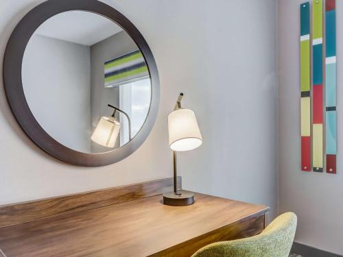 a mirror and a desk with a lamp and a chair at Hampton Inn & Suites Cincinnati Midtown Rookwood in Cincinnati