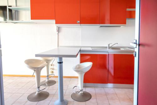 a kitchen with red cabinets and a table and stools at SE040 - Senigallia, bilocale fronte mare con giardino in Scapezzano