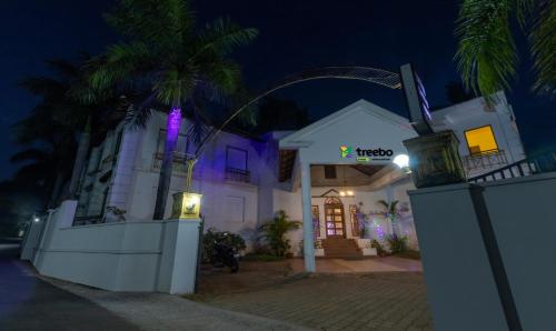 a white building with a neon sign on it at night at Treebo Trend Sadhoo Heritage Ayurvedic Spa & Pool in Kannur