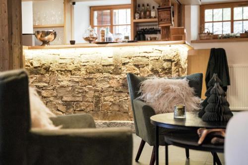 Habitación con sillas, mesa y pared de piedra. en Hôtel Restaurant La Ferme de Cupelin, en Saint-Gervais-les-Bains