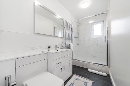 y baño blanco con aseo y ducha. en Penthouse 1BR flat wbalcony & city view, Walworth, en Londres