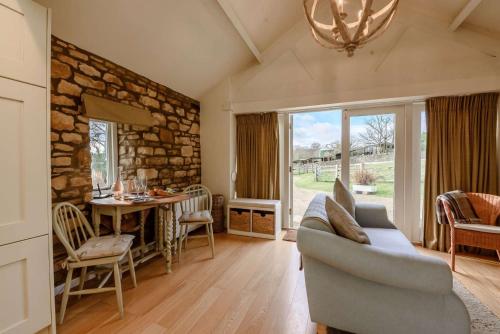 a living room with a couch and a stone wall at Oxbow Cottage in Stow on the Wold