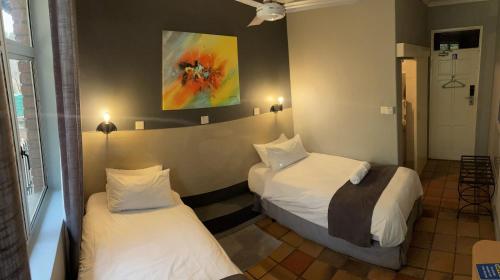 a hotel room with two beds and a painting on the wall at N1 Hotel & Campsite Victoria Falls in Victoria Falls