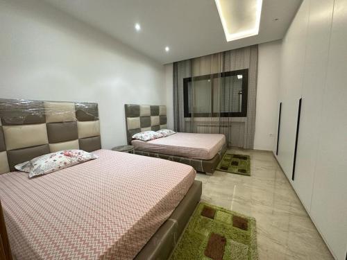 a bedroom with two beds and a television in it at Luxueux S+2 Menzah5 in Ariana