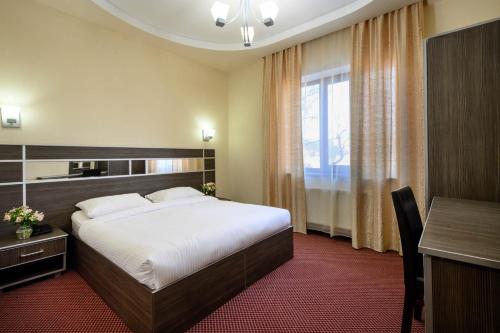 a hotel room with a large bed and a desk at Alpina Resort by Stellar Hotels, Tsaghkadzor in Tsaghkadzor