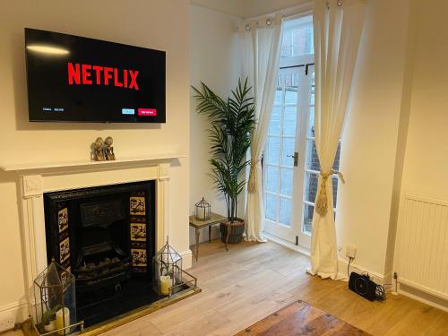 a living room with a television above a fireplace at Newly Refurbished City Centre House With Parking in Exeter