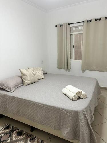a white bedroom with a bed with towels on it at Apartamento 5 a 4 min da Basílica in Aparecida