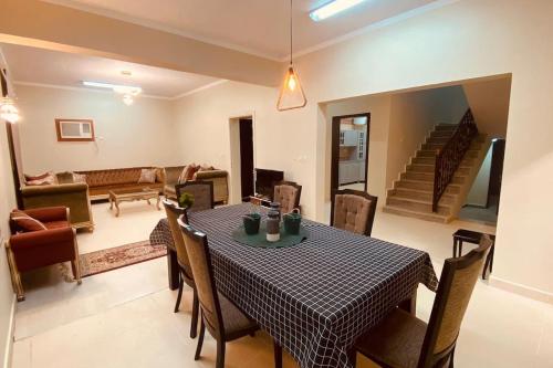 a dining room with a table and chairs and a living room at Palm Villa in AlUla