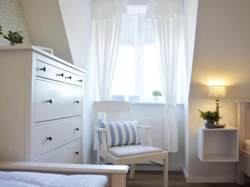 a bedroom with a dresser and a chair and a window at Holiday apartment Domstag in Kronsgaard