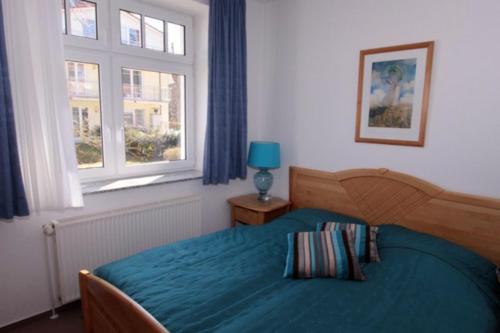 - une chambre avec un lit bleu et une fenêtre dans l'établissement Strandvilla Drei Mäderl Haus, à Boltenhagen
