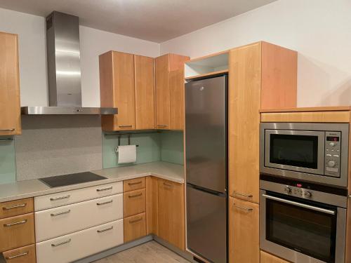 a kitchen with wooden cabinets and a stainless steel refrigerator at Apartment im Herzen von Neusiedl am See in Neusiedl am See