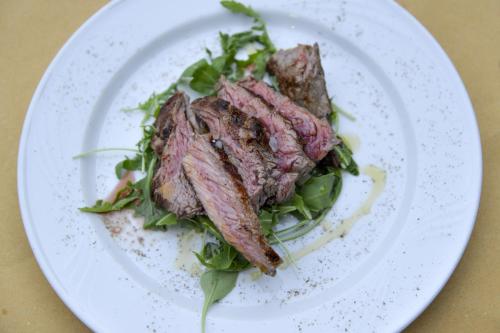 a white plate with a piece of meat on a salad at Casa Di Campagna In Toscana in Sovicille