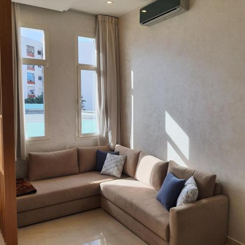 a living room with a couch and two windows at Le Petit Bijou in Tetouan