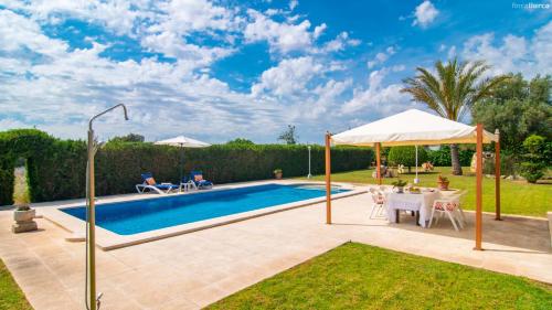 a swimming pool with a table and a white umbrella at Finca Mafedo in Lloseta