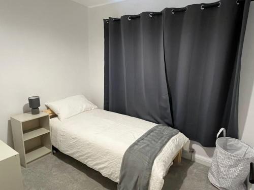 ビーストンにある3BD Sanctuary in Beeston, Nottinghamshireのベッドルーム1室(黒いカーテン付きのベッド1台付)