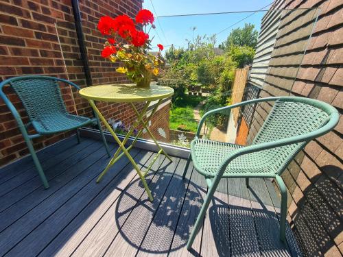 two chairs and a table with a vase of flowers on a porch at The Hideaway - Central Wareham, Roof terrace, Garden & Parking in Wareham