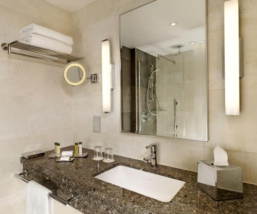 y baño con lavabo y espejo. en DoubleTree by Hilton London Victoria en Londres