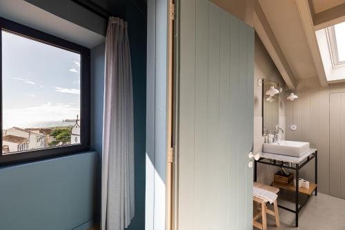 uma casa de banho com um lavatório e uma grande janela em Guava Azores II em Ribeira das Tainhas