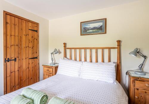 ein Schlafzimmer mit einem Bett mit einem Kopfteil aus Holz und zwei Lampen in der Unterkunft 5 Swallowsholm Cottage in Richmond