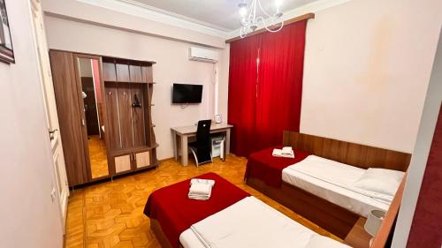 a room with two beds and a desk and a television at Elross Hotel in Yerevan