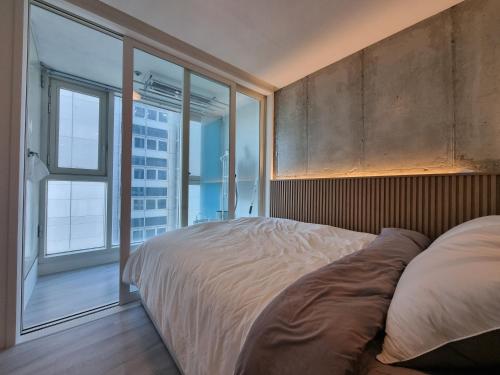 ein Schlafzimmer mit einem großen Bett und einem großen Fenster in der Unterkunft Ville apartment Sunneung Station&Coex free wifi in Seoul