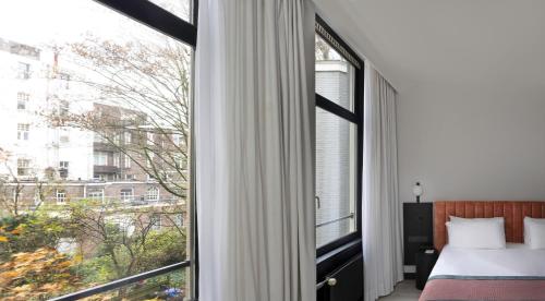 a bedroom with a bed and a large window at Catalonia Vondel Amsterdam in Amsterdam