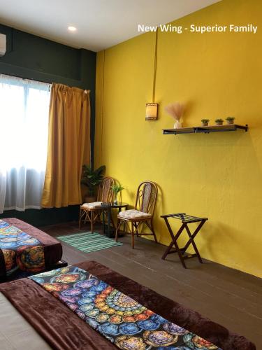 a bedroom with yellow walls and two chairs and a table at Rope Walk Guest House in George Town