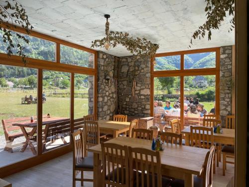 ein Restaurant mit Holztischen, Stühlen und Fenstern in der Unterkunft Petriti theth in Theth