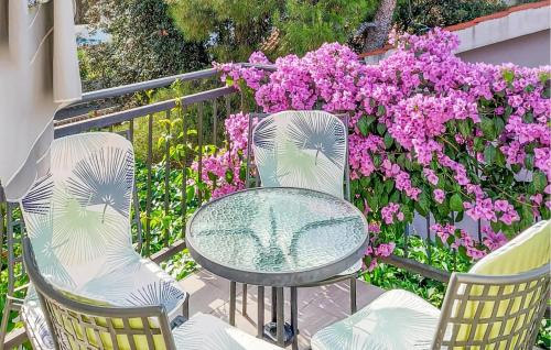 trois chaises et une table et quelques fleurs roses dans l'établissement Stunning Apartment In Brodarica, à Brodarica