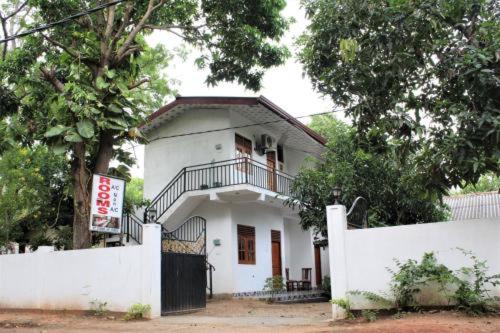a white house with a balcony and a fence at ගයාන් ගෙස්ට් කතරගම in Kataragama