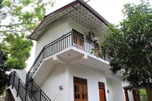 a white house with a balcony on top of it at ගයාන් ගෙස්ට් කතරගම in Kataragama