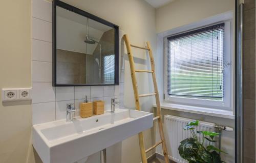 La salle de bains est pourvue d'un lavabo blanc et d'un miroir. dans l'établissement Pet Friendly Home In Kerkdriel With Lake View, à Kerkdriel