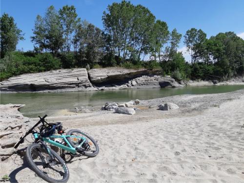 a bike parked on a sandy beach next to a river at Casa Olimpia in Priocca