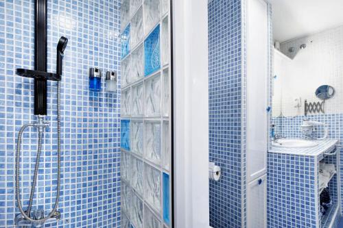y baño de azulejos azules con ducha y lavamanos. en El Marinero, en Rota