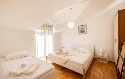 two beds in a room with white walls and wooden floors at Lovely Home In Trilj With Heated Swimming Pool in Trilj