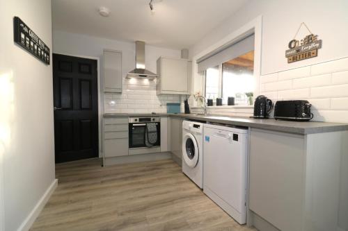 een keuken met een wasmachine en droger. bij Signature - Sunnyside House in Holytown
