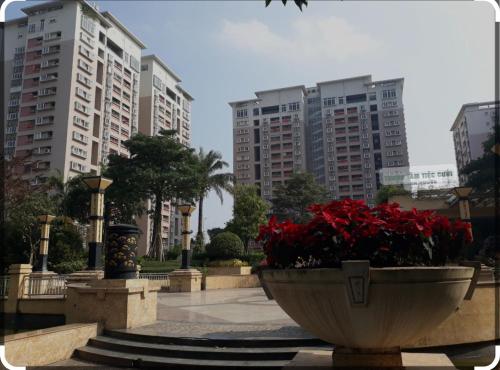 a park with red flowers and tall buildings at Căn hộ 80m, 2 ngủ 2 vệ sinh-2 bedrooms apartment in Trương Lâm