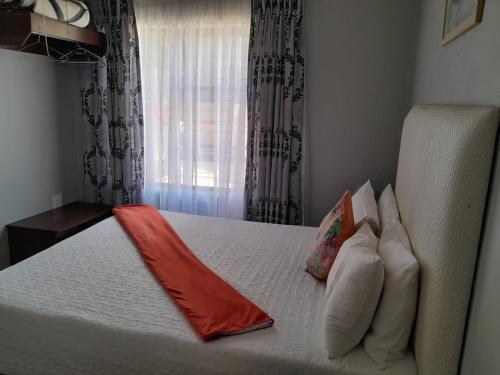 a bedroom with a bed with a red pillow on it at Reitumetse GuestHouse in Maseru
