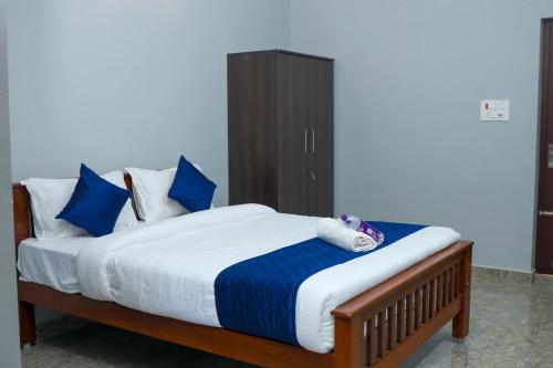 a bedroom with a bed with blue and white pillows at Bay Walk Residency in Auroville