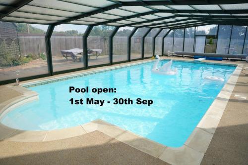 a swimming pool in a building with the words pool open may at The Peacock Nest - Bell Tent in Sittingbourne