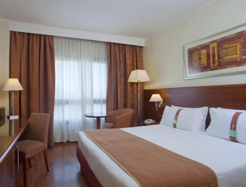 una camera d'albergo con un grande letto e una finestra di Holiday Inn Cagliari, an IHG Hotel a Cagliari