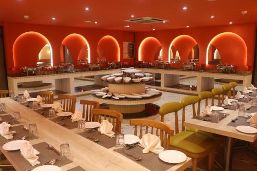 a restaurant with long tables and chairs and orange walls at SK Premium Park, World Square Mall in Ghaziabad