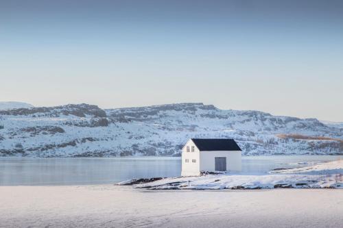 a small house on an island in a body of water at Gistihúsið - Lake Hotel Egilsstadir in Egilsstadir
