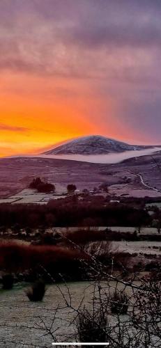 a sunset over a field with a hill in the background at Old Post Office in Linsfort