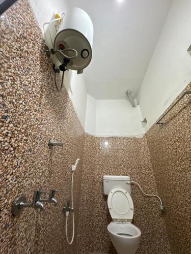 een badkamer met een toilet, een douche en een spotlight bij SITARAM DORMITORY in Brahmapur